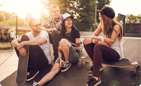 Young happy friends sitting in the skate park at sunset and communicating.