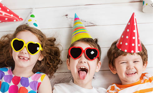 Happy child friend in carnival party, lying on a wooden floor. Happy childhood concept. High top view.