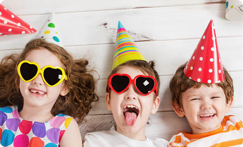 Happy child friend in carnival party, lying on a wooden floor. Happy childhood concept. High top view.