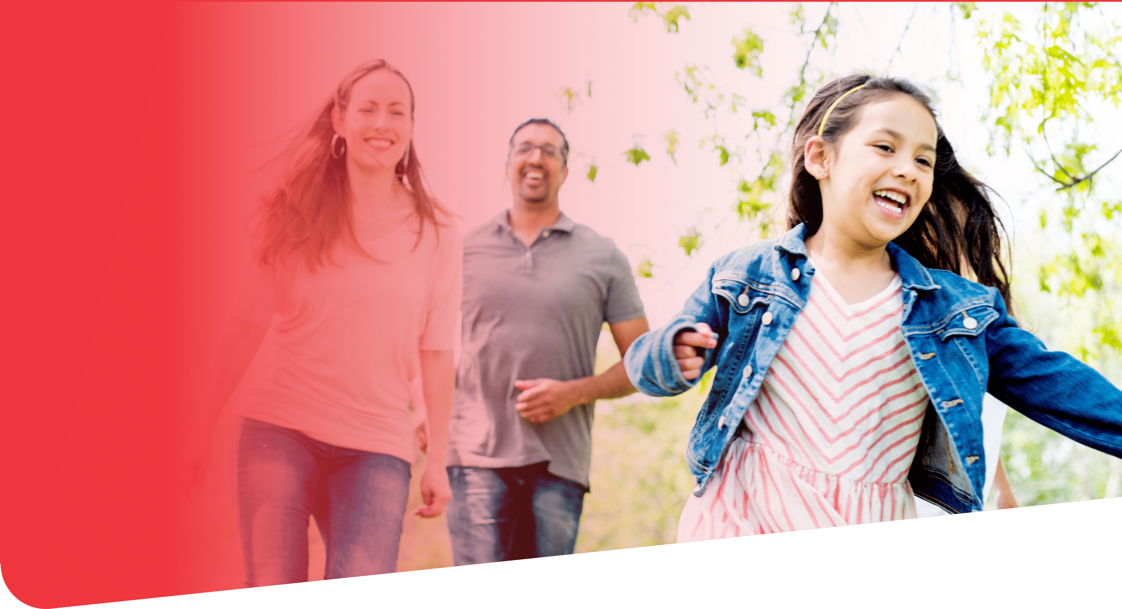 A multi-ethnic family is playing together, running through the park, outside on a beautiful sunny day.