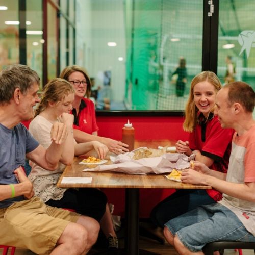 Two Y staff and three others sitting at a table eating hot chips and laughing