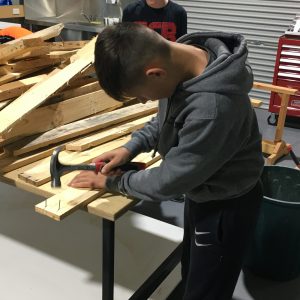 Young person hammering nails into a piece of wood