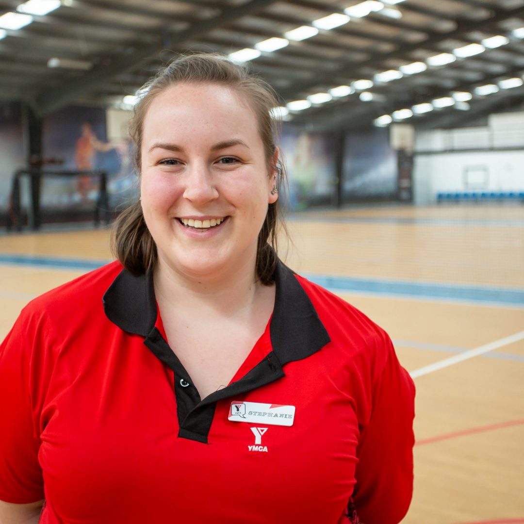 Smiling Stephanie in red YMCA polo shirt in the multi-purpose courts